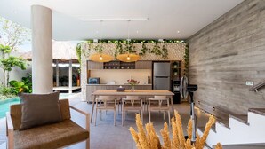 Une cuisine moderne avec un coin repas, une grande fenêtre et une piscine en arrière-plan.