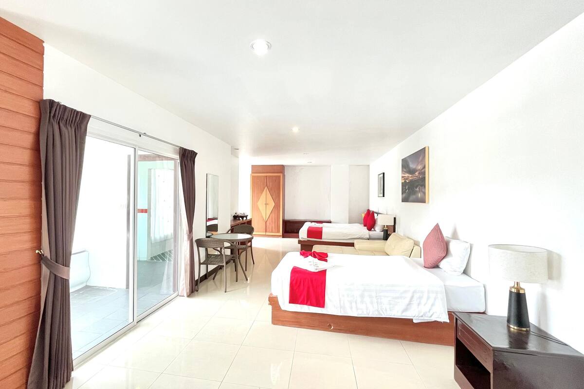 Une chambre d’hôtel avec un grand lit, un lit plus petit, un bureau et une armoire.