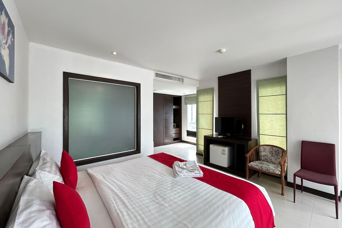 Une chambre d’hôtel moderne équipée d’un grand lit, d’une télévision, d’un bureau et d’une chaise.
