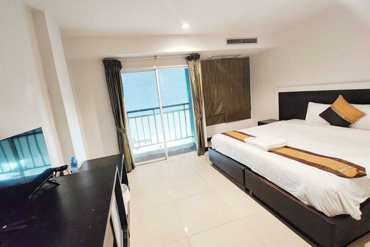 Une chambre d’hôtel avec un lit, une télévision, un balcon avec des rideaux et une vue sur la mer.