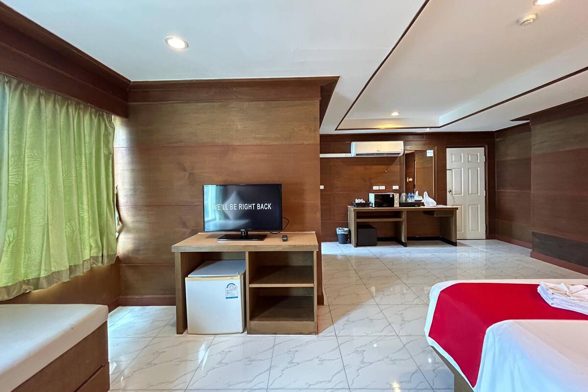 Une chambre d’hôtel équipée d’une télévision, d’un bureau avec un ordinateur, d’un lit et d’un petit réfrigérateur.