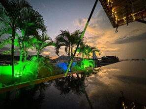 A rooftop pool area with palm trees and a sunset view. - Cocoon APK Resort and SPA Hotel (Patong)