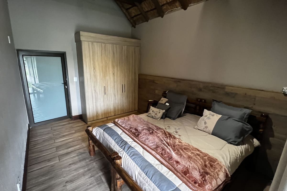 A bedroom with a wooden bed, a wardrobe, and a door leading to a balcony.