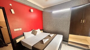 A hotel room with a bed, a wardrobe, and a red accent wall. - HOTEL GRAND HIGHWAY (Faridabad)