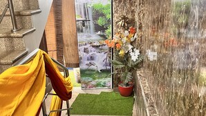 A staircase leading to a room with a waterfall mural, a potted plant, and a green mat. - HOTEL GRAND HIGHWAY (Faridabad)
