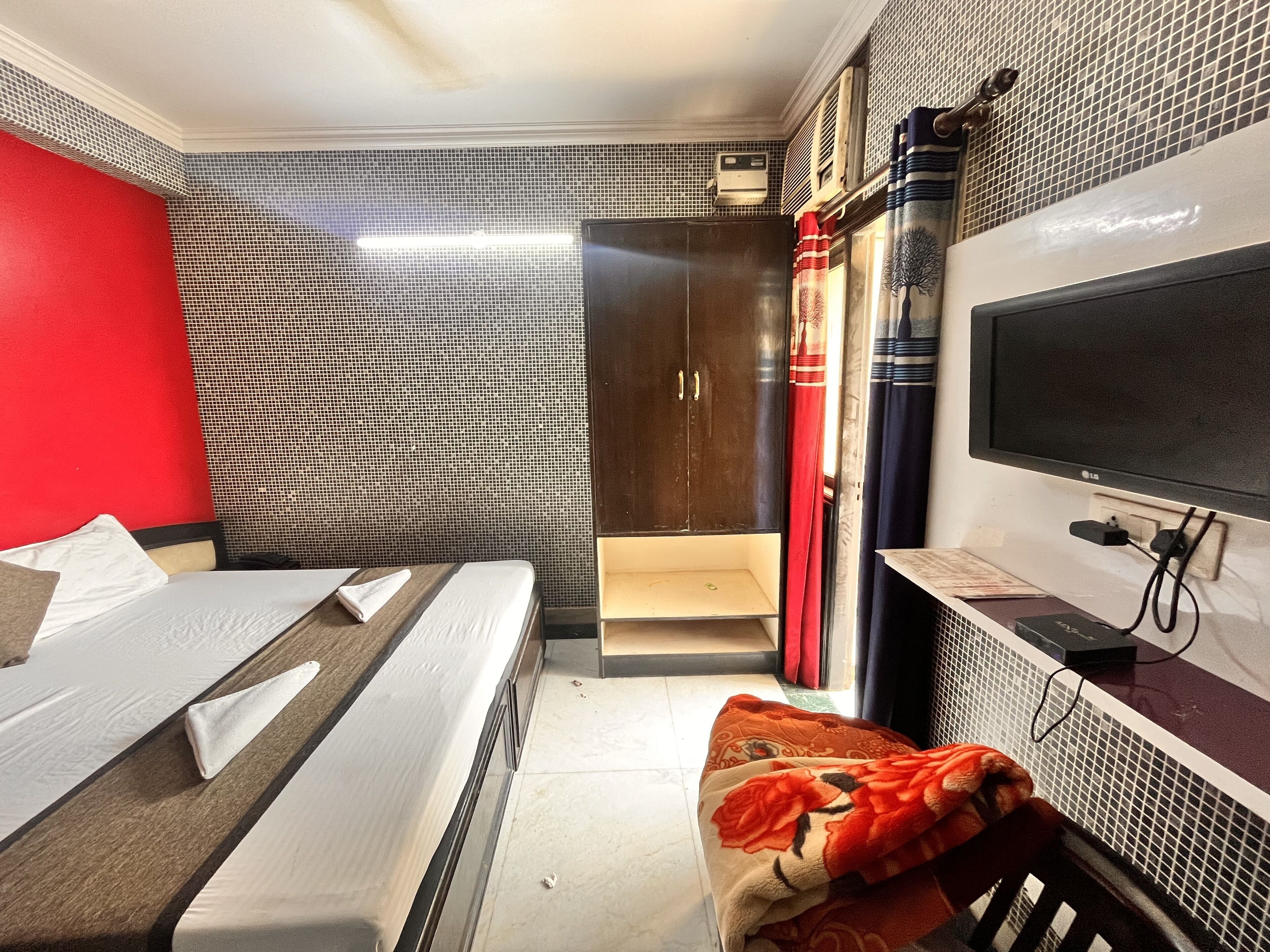 Een hotelkamer met een bed, een bureau met een computer, een televisie en een kledingkast.