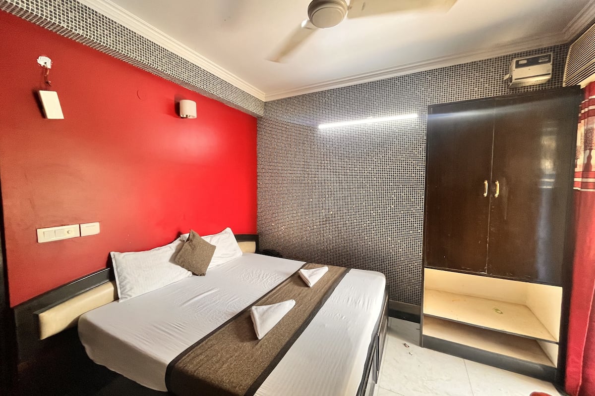 A hotel room with a bed, a wardrobe, a ceiling fan, and a wall-mounted air conditioner.
