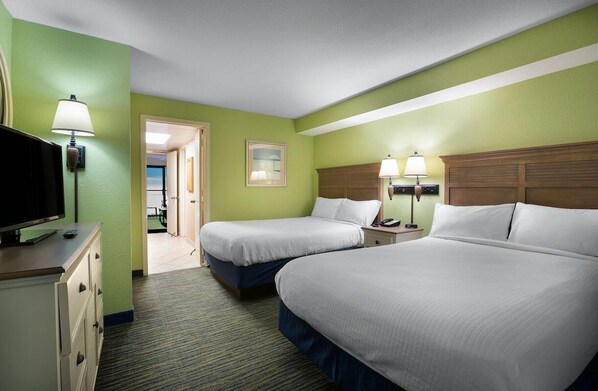 A hotel room with two beds, a television, and a desk with drawers. - Beachside Haven: Double Suites with Ocean Views (Myrtle Beach)