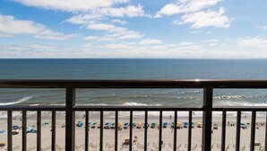 A beach view from a balcony with a railing, ocean, and beach umbrellas. - Beachside Haven: Double Suites with Ocean Views (Myrtle Beach)
