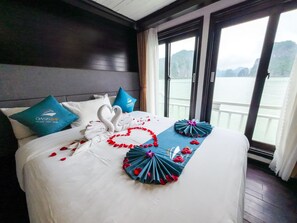 A hotel room with a bed, a large window, and a view of the water. - Oasis Party Cruise (Tuan Chau)