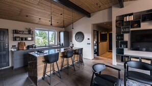 A modern kitchen with a central island, black bar stools, and a large window.