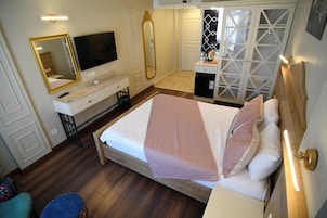 A hotel room with a bed, a TV, a mirror, a wardrobe, and a desk.