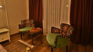 A room with two patterned armchairs, a small table with a glass, and a wooden floor. - SUR PALACE HOTEL (Diyarbakir)