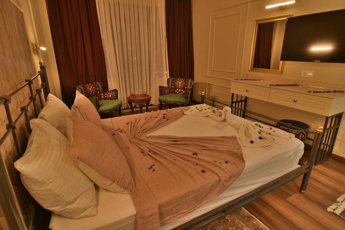 A hotel room with a bed, a TV, a desk, and two chairs.