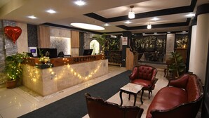 A reception area with a marble counter, a red heart balloon, and a sign that reads "RECEPTION." There are leather chairs and a small table in the foreground. - SUR PALACE HOTEL (Diyarbakir)