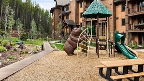 A lodge with a play area including a slide, a bear sculpture, and a picnic table. - Grand Lodge at Peak 7 - 3 Bedroom Residence - Pool, Hot Tubs, Game Room & More! (Breckenridge)