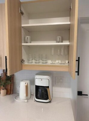 Kitchen area with cabinet, coffee maker, and coffee pot.