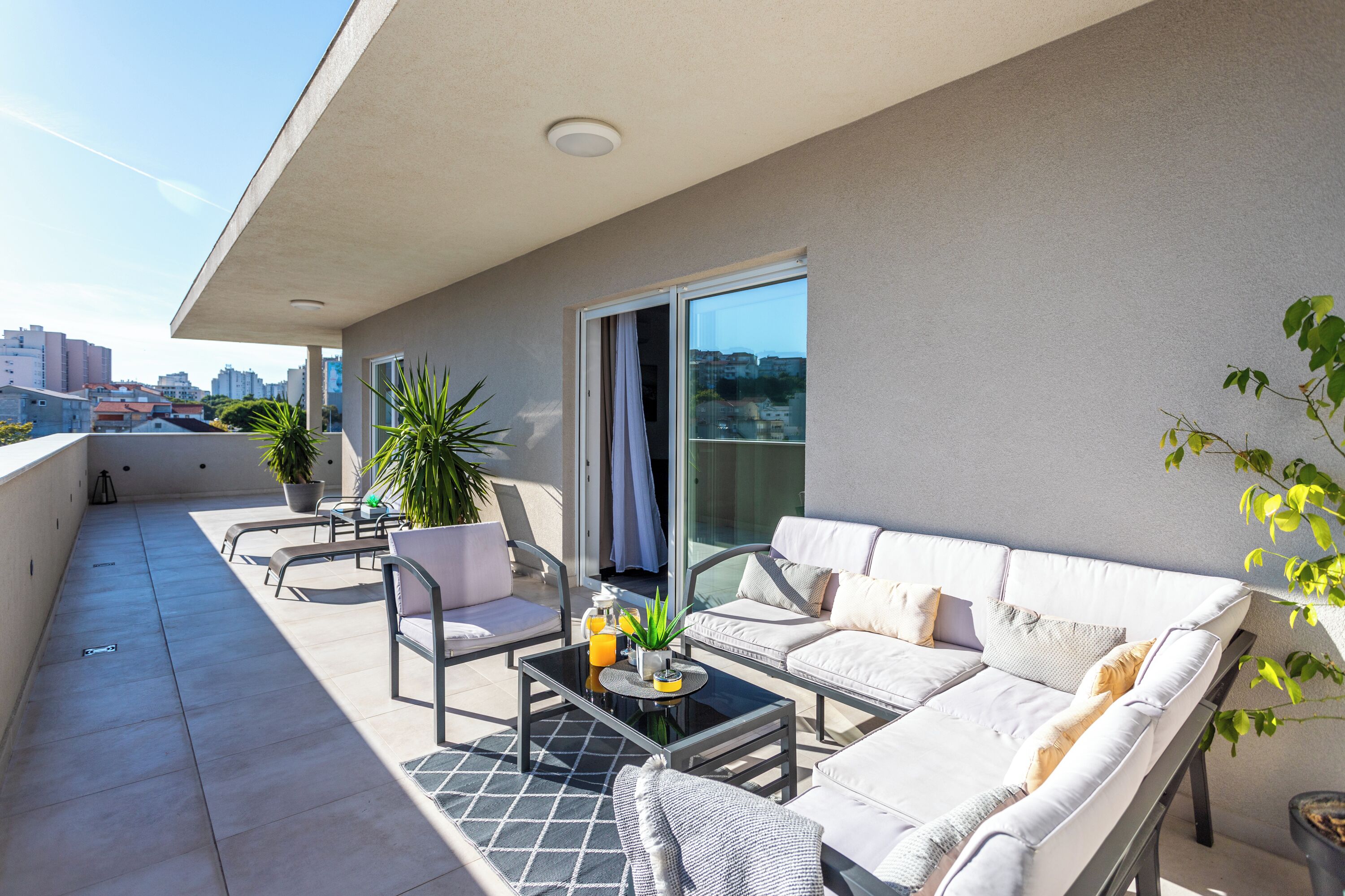 A balcony with a sofa, chairs, and a table.