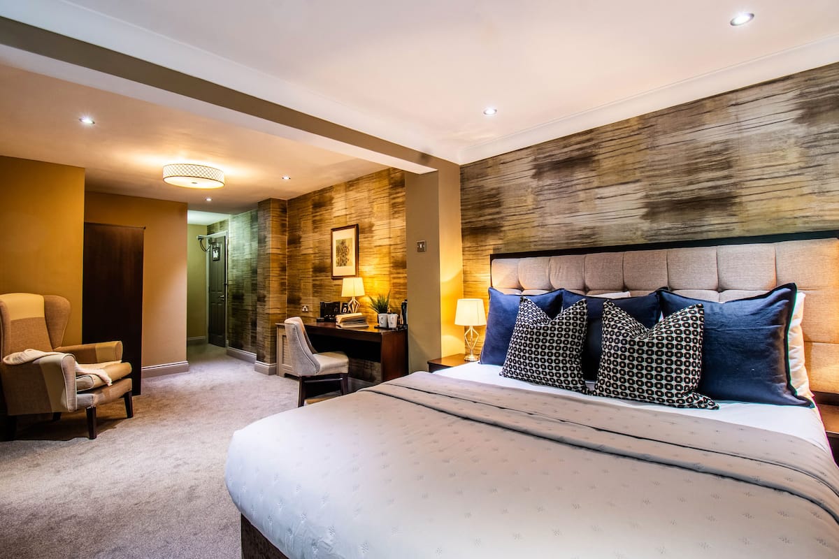 A hotel room with a large bed, a desk, a chair, and a wall with a textured design.