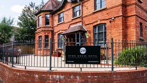 A brick building with a sign for Eton House Hotel, featuring a car park and main entrance. - Eton House (Yeovil)