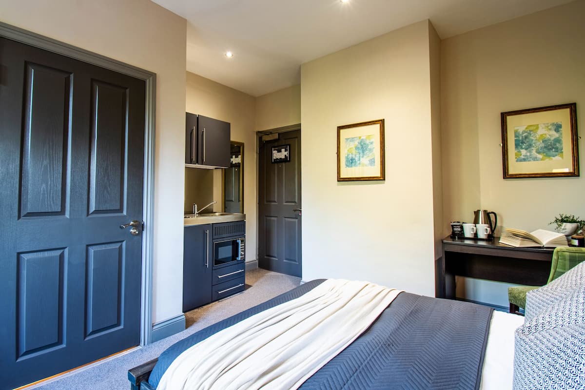 A bedroom with a bed, a desk, a chair, a wardrobe, and a door.