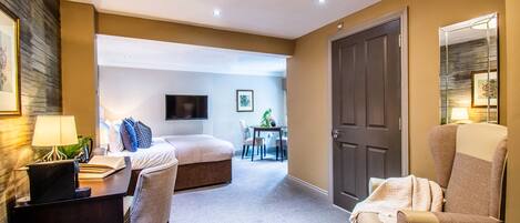 A hotel room with a bed, desk, chair, and a TV.