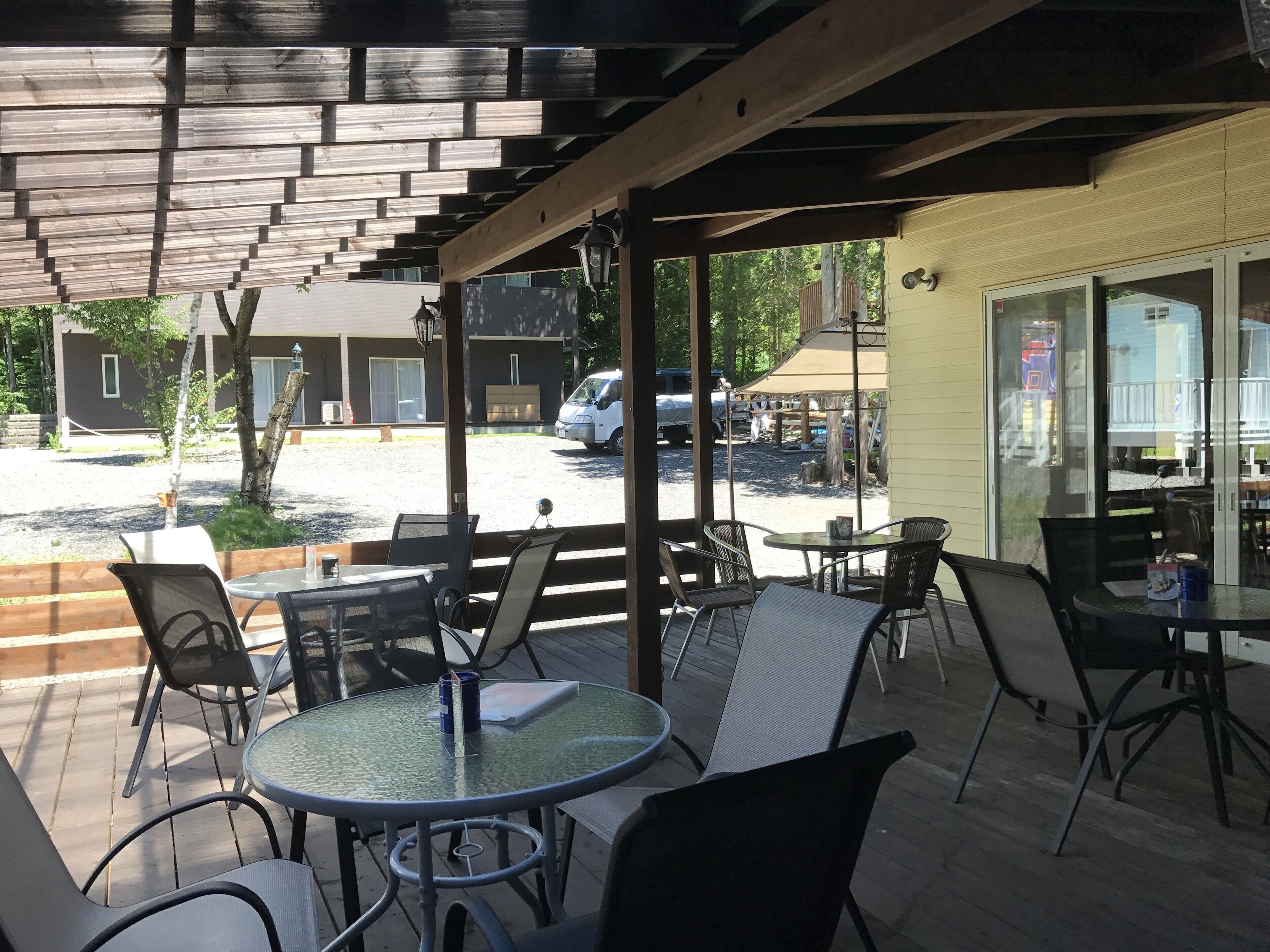 An outdoor patio with round tables and chairs, a covered seating area, and a view of the street.