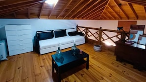 Una stanza in stile loft con soffitto in legno, un divano bianco, un tavolino e una scrivania con un computer.
