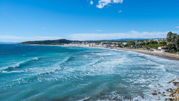A coastal view with a beach, ocean waves, and a distant town. - Holiday Home 'Ca La Montse' with Sea View, Private Terrace and Wi-Fi (Altafulla)