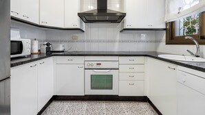 A kitchen with white cabinets, a black range hood, a built-in oven, a microwave, and a sink. - Holiday Home 'Ca La Montse' with Sea View, Private Terrace and Wi-Fi (Altafulla)