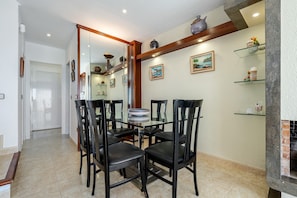 Un espace repas avec une table en verre entourée de chaises, un sol carrelé et une cheminée en briques.