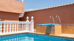 Zwembad met een witte balustrade, blauwe rand en betegelde wand.