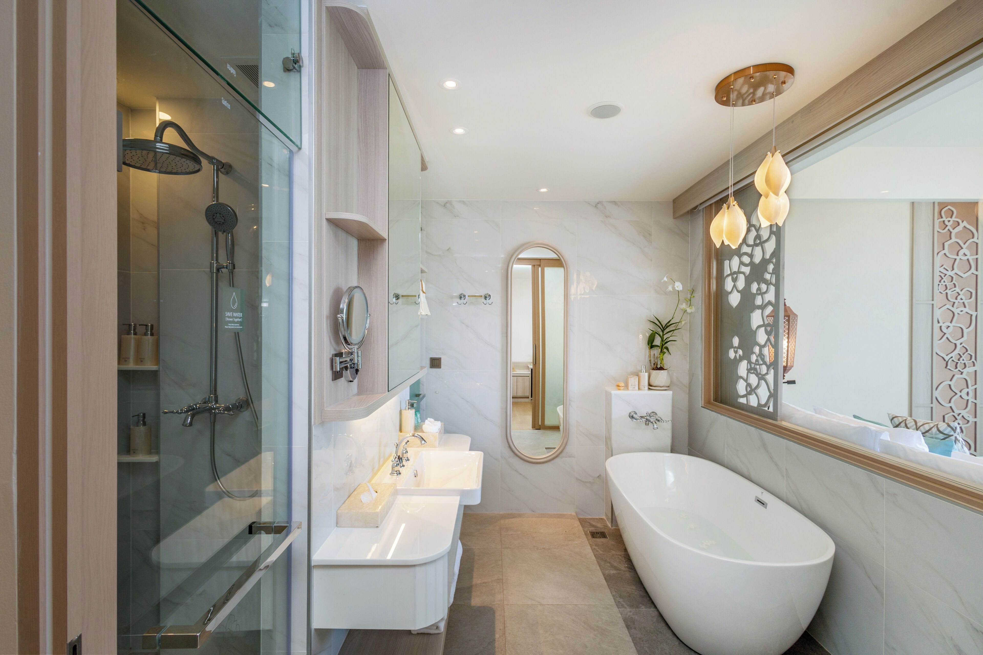 Un baño moderno con ducha de vidrio, una bañera independiente y un tocador con tres lavamanos.