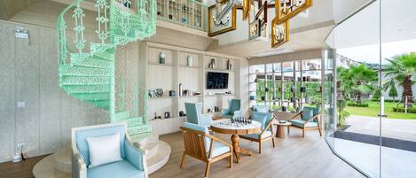 A spacious lobby with a spiral staircase, seating areas, and a large window offering a view of the outdoors.