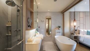 A modern bathroom with a glass-enclosed shower, a freestanding bathtub, and a vanity with two sinks.
