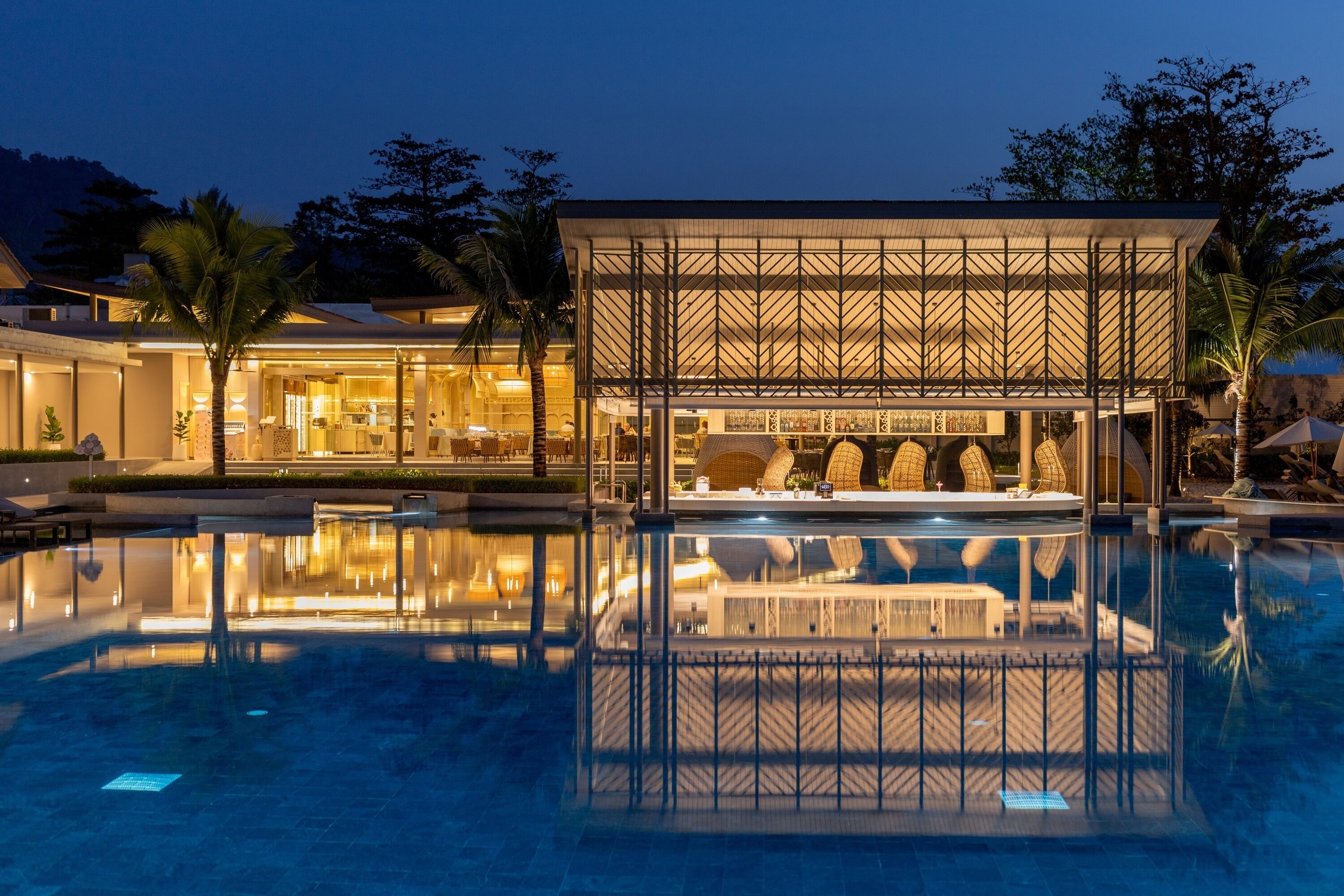A modern hotel with a pool, a bar, and a dining area.