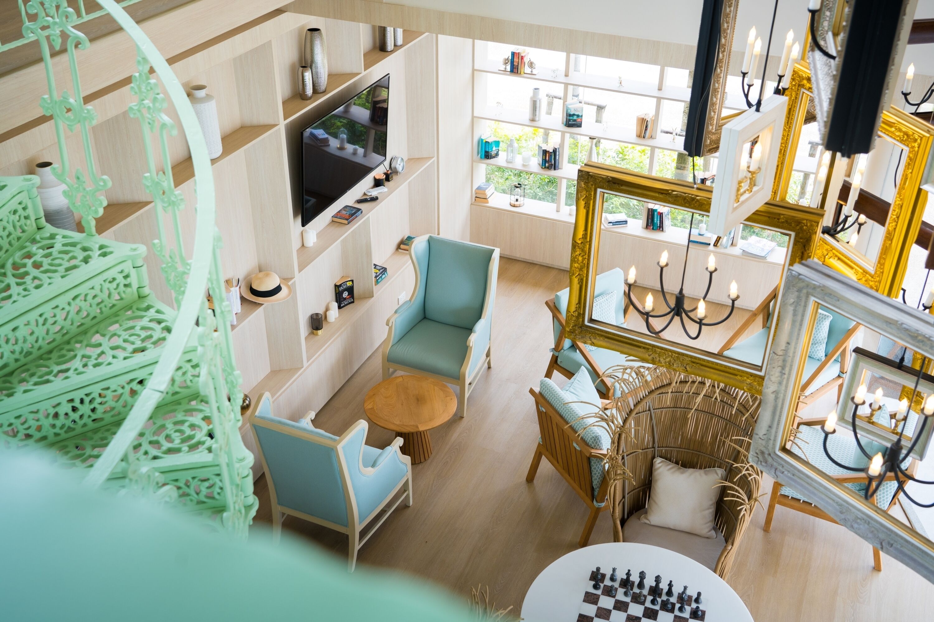 Una habitación con televisión, estanterías, sofá, sillón, mesa redonda y un tablero de ajedrez.