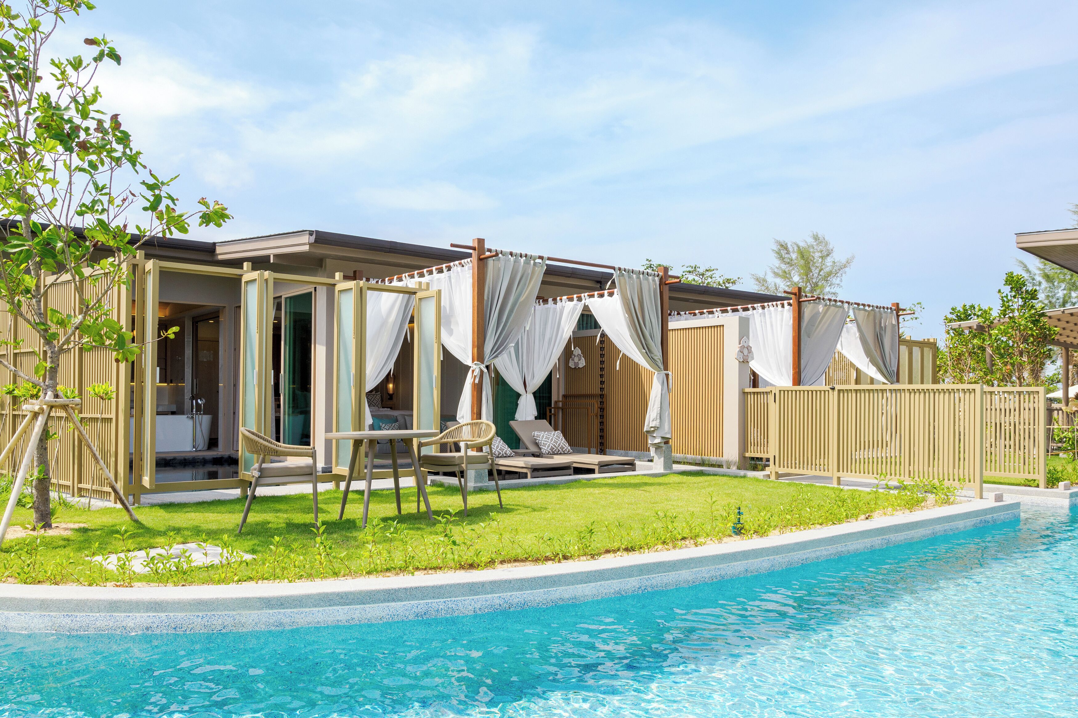 Villa junto a la piscina con baño privado, mobiliario de exterior y un patio cubierto.