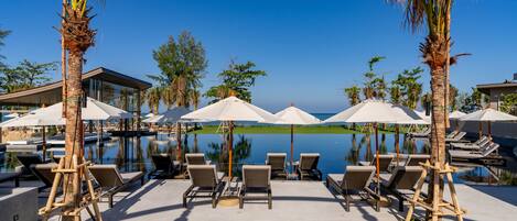 A poolside area with lounge chairs and umbrellas, overlooking a calm body of water.