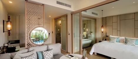 A modern hotel room with a sofa, a small round table, a bed, and a large window.
