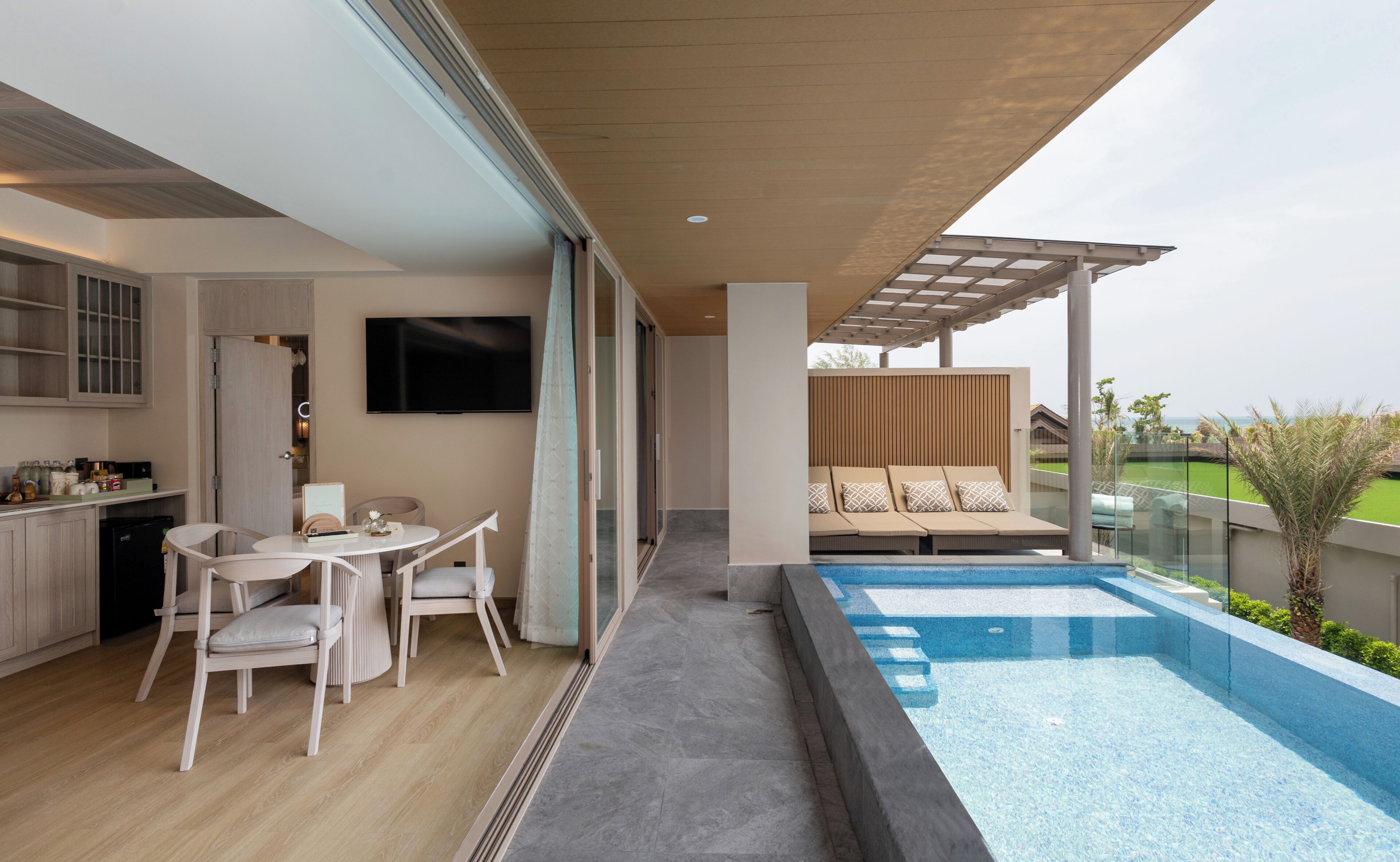 A modern outdoor living space with a pool, a dining area, and a seating area with a view.