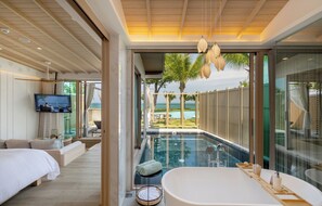 A modern hotel room with a large bed, a TV, a glass-enclosed swimming pool, and a view of the sea. - The Little Shore Khao Lak by Katathani (Takua Pa)