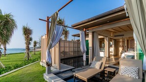 A modern outdoor lounge area with a pool, seating, and a view of the sea.