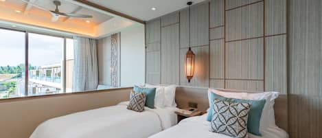 Une chambre d’hôtel avec deux lits, un ventilateur de plafond, une grande fenêtre donnant sur un beau paysage et un luminaire fixé au mur.