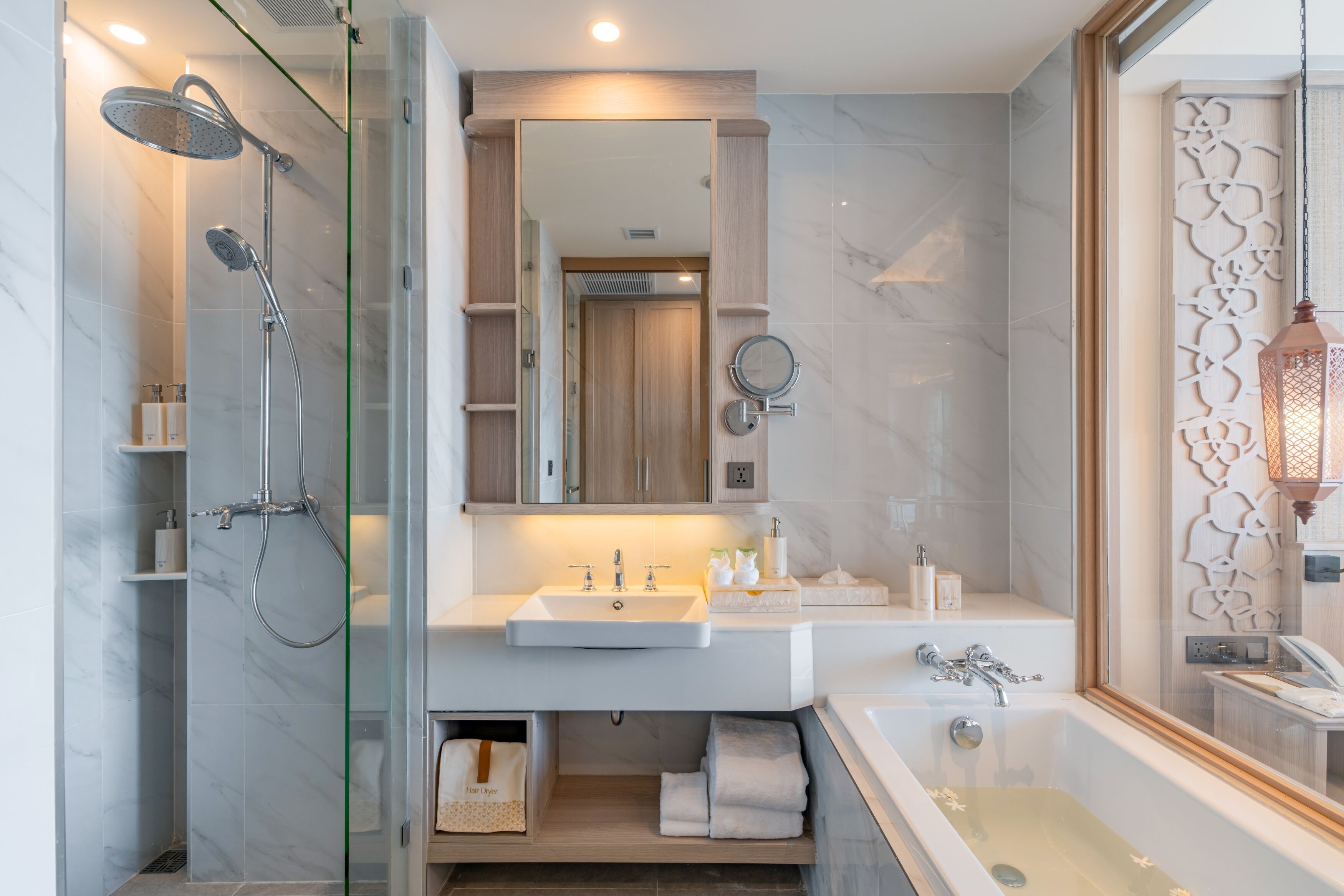 A modern bathroom with a glass-enclosed shower, a large mirror, a sink, and a bathtub.