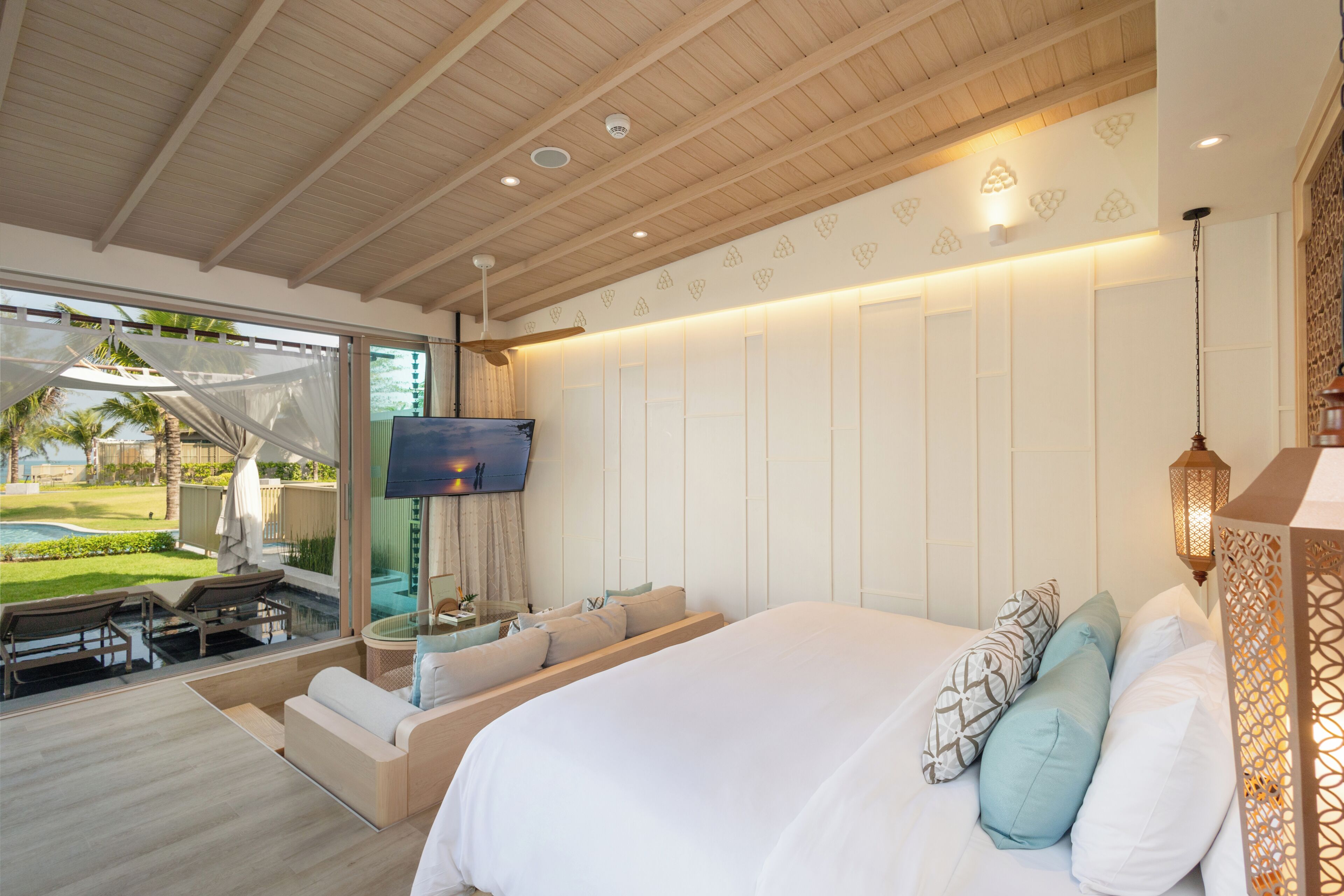 Een slaapkamer met een groot bed, een televisie en uitzicht op een zwembad en tuin.