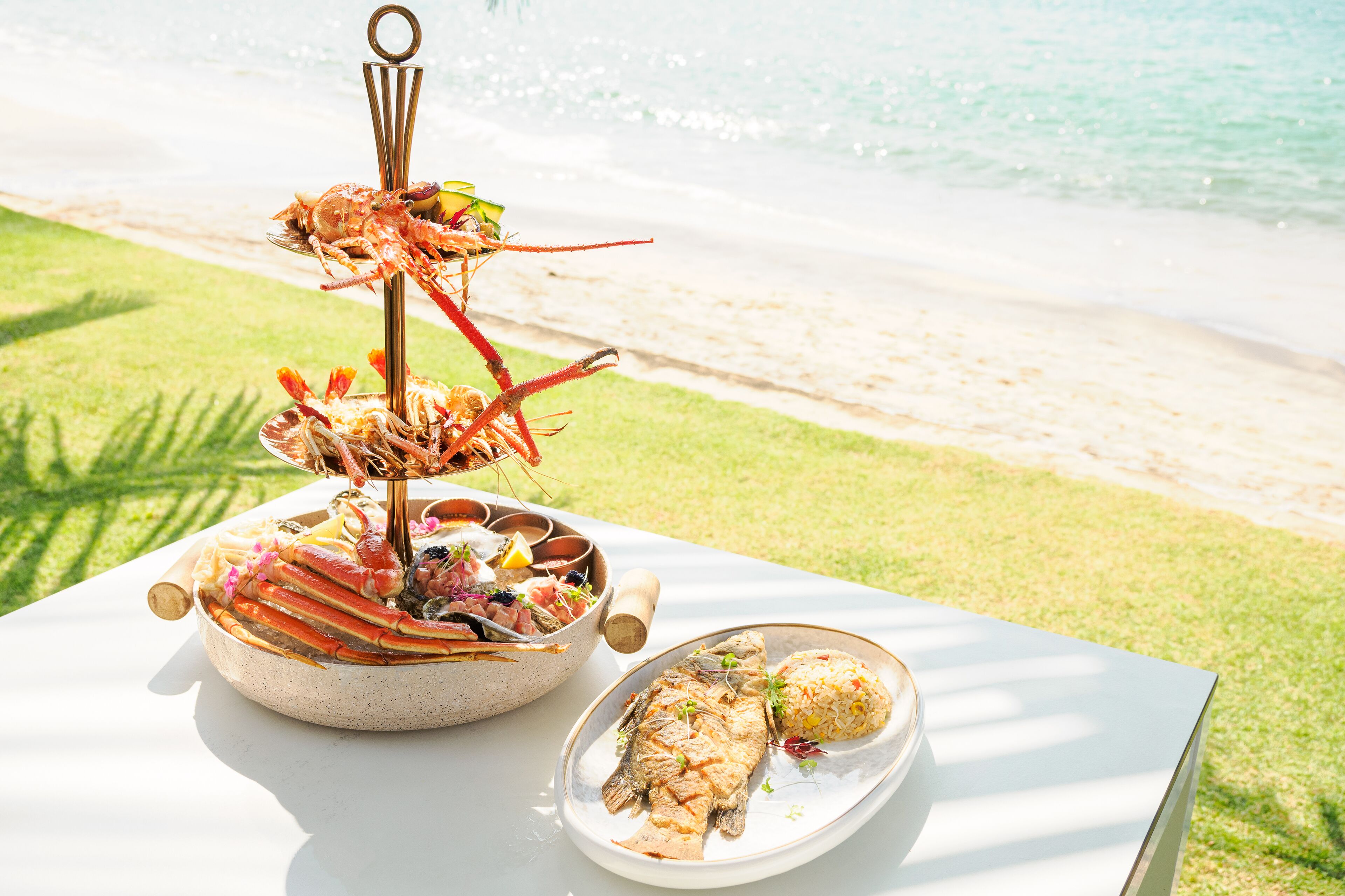 A seafood platter with crab and fish on a table by the beach.