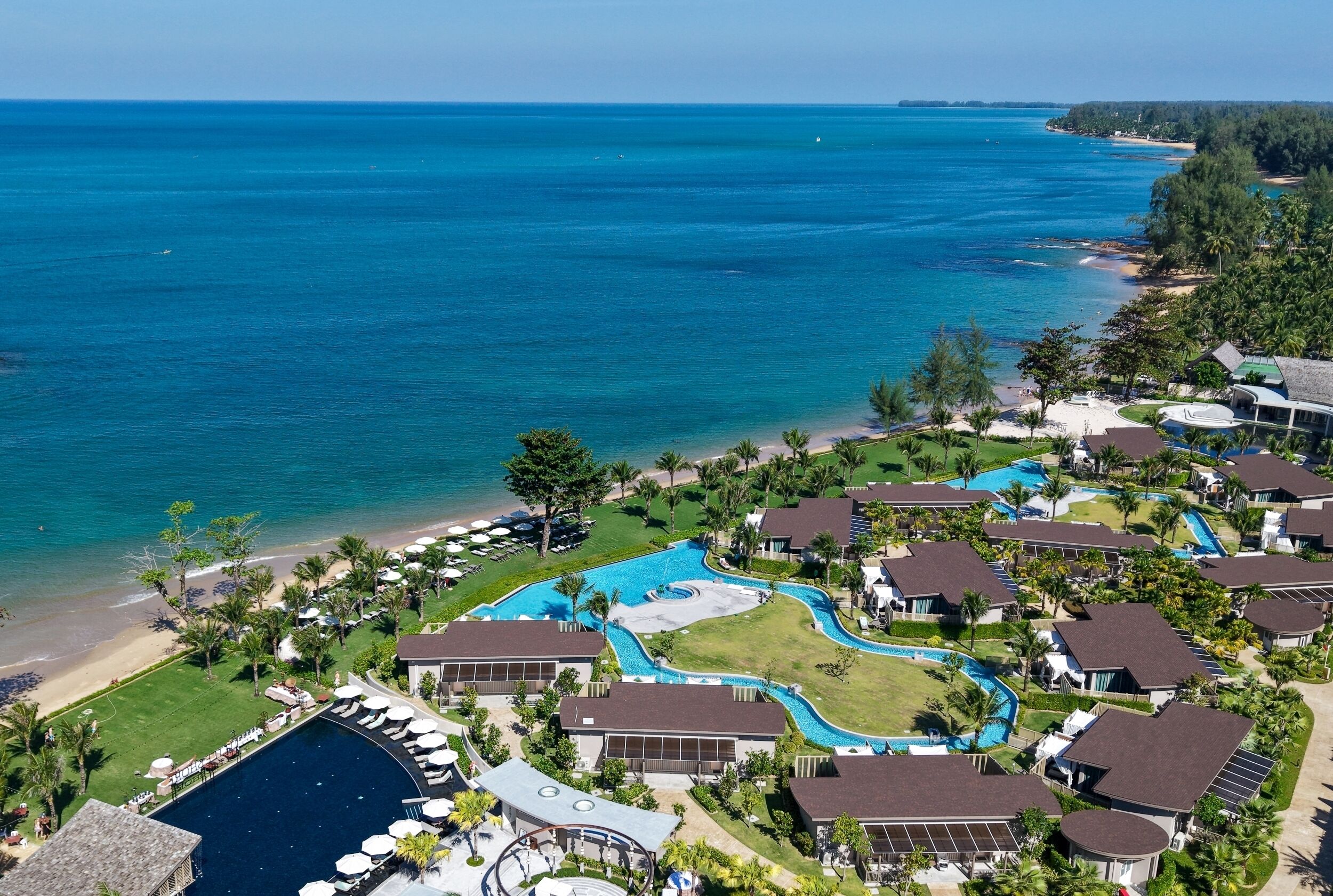 A resort with multiple swimming pools, beachfront access, and lush greenery.