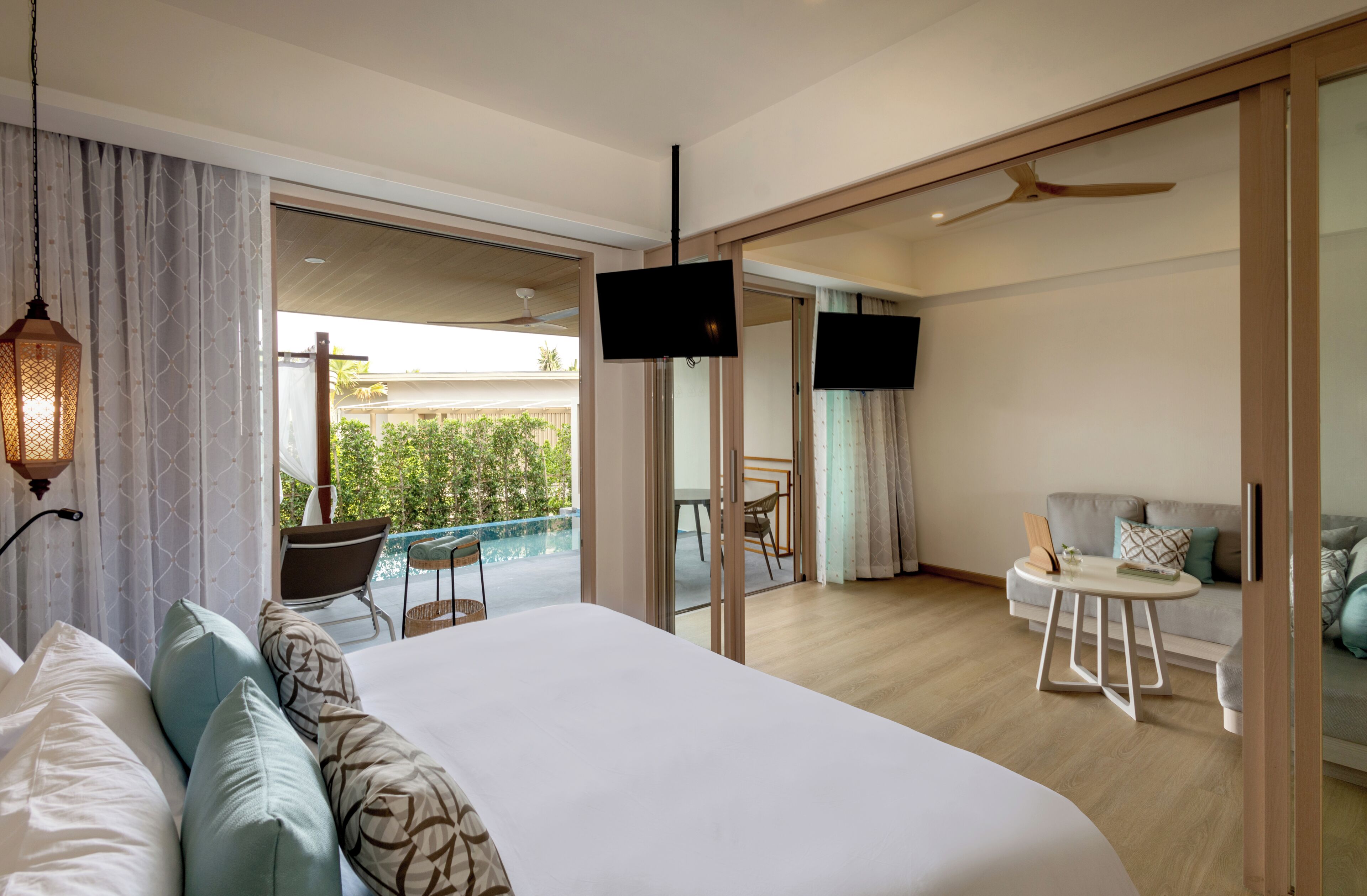 A hotel room with a bed, a TV, a balcony with a chair, and a sofa.