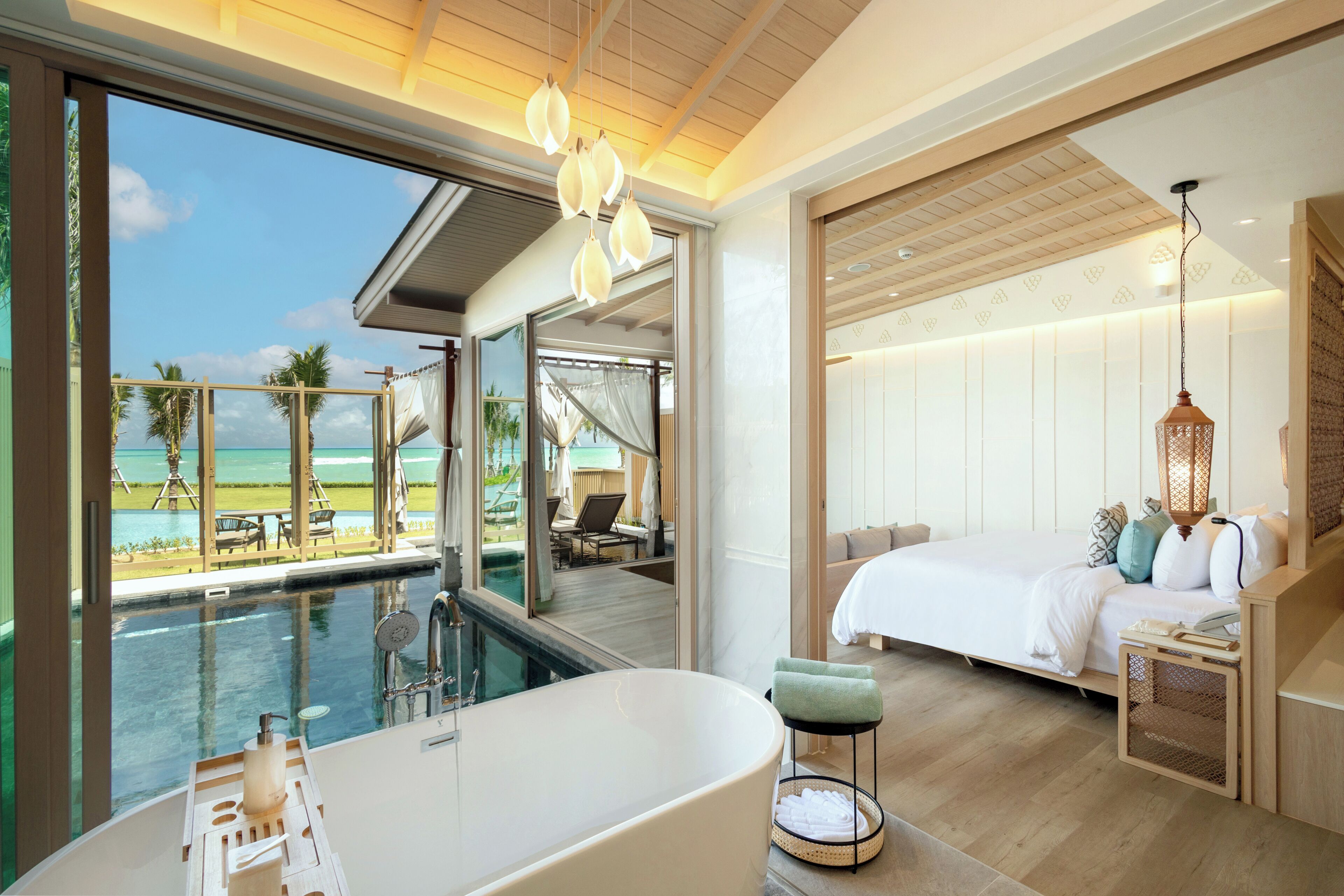 Habitación de hotel moderna con una bañera grande, una cama y vista al océano.